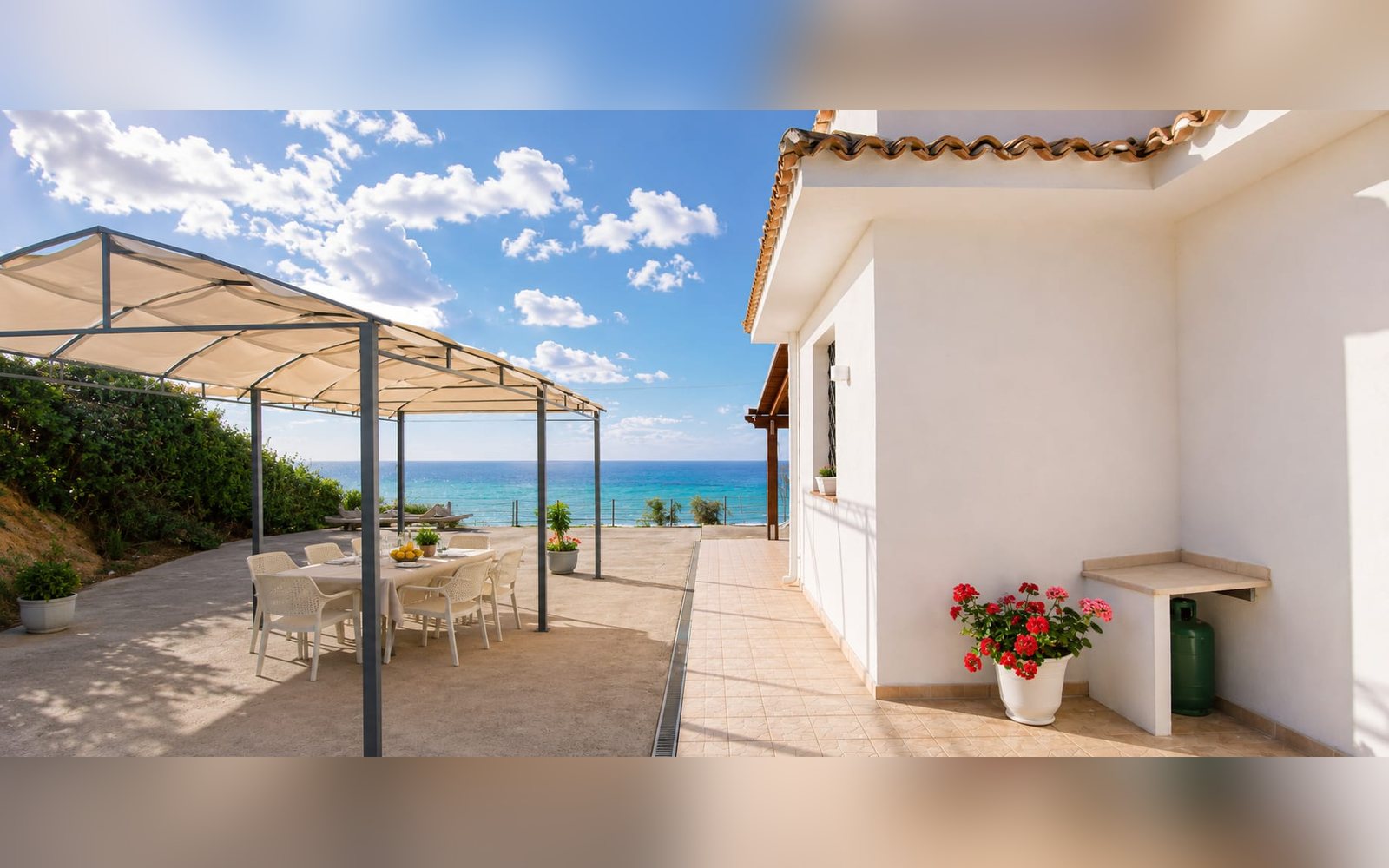 Pergolato esterno con tavolo, davanti alla facciata della villa