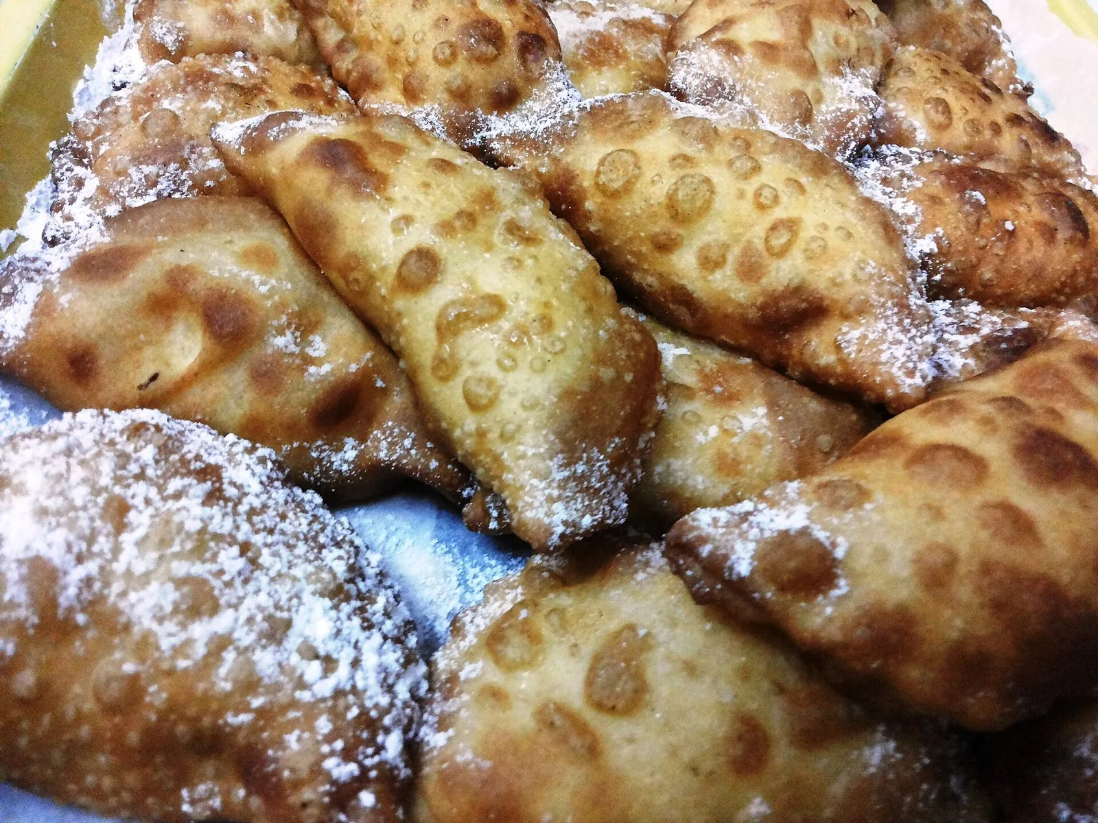 Cassatelle siciliane fritte e spolverate di zucchero a velo su un piatto